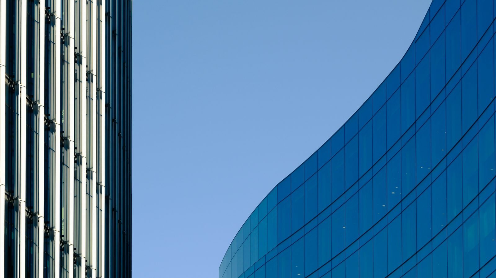 Arquitectura de oficinas: fachada de vidrio curva sobre cielo azul.